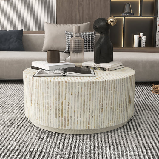 Round marble coffee table in a living room setting with books and decorative items.