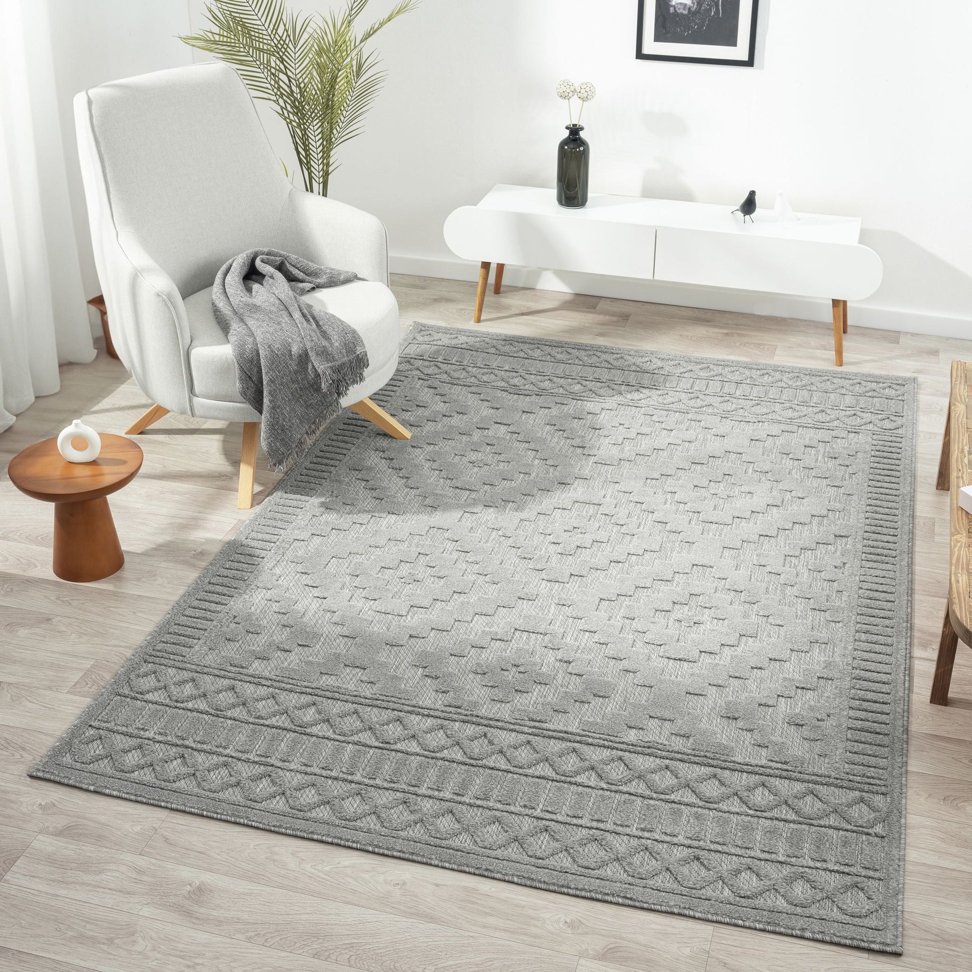 Gray textured rug in a living room setting with a white armchair and coffee table.