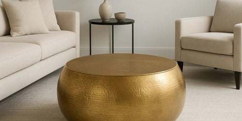 Gold hammered drum coffee table between a cream sofa and armchair in a neutral living room