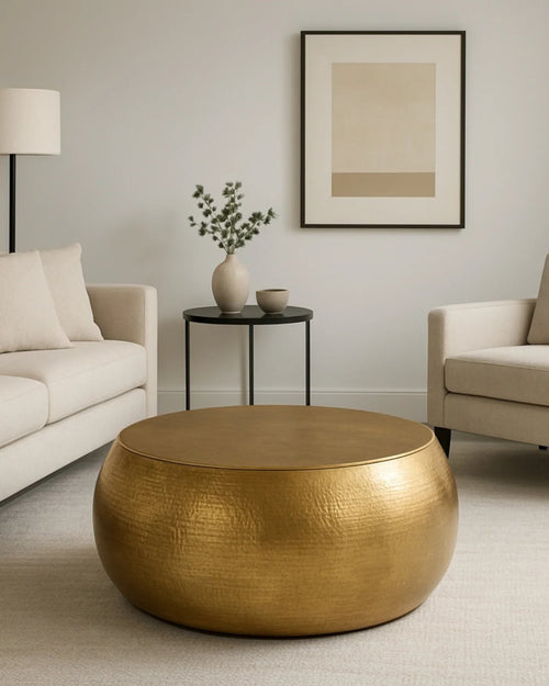 Gold hammered drum coffee table in a neutral living room with a cream sofa and armchair